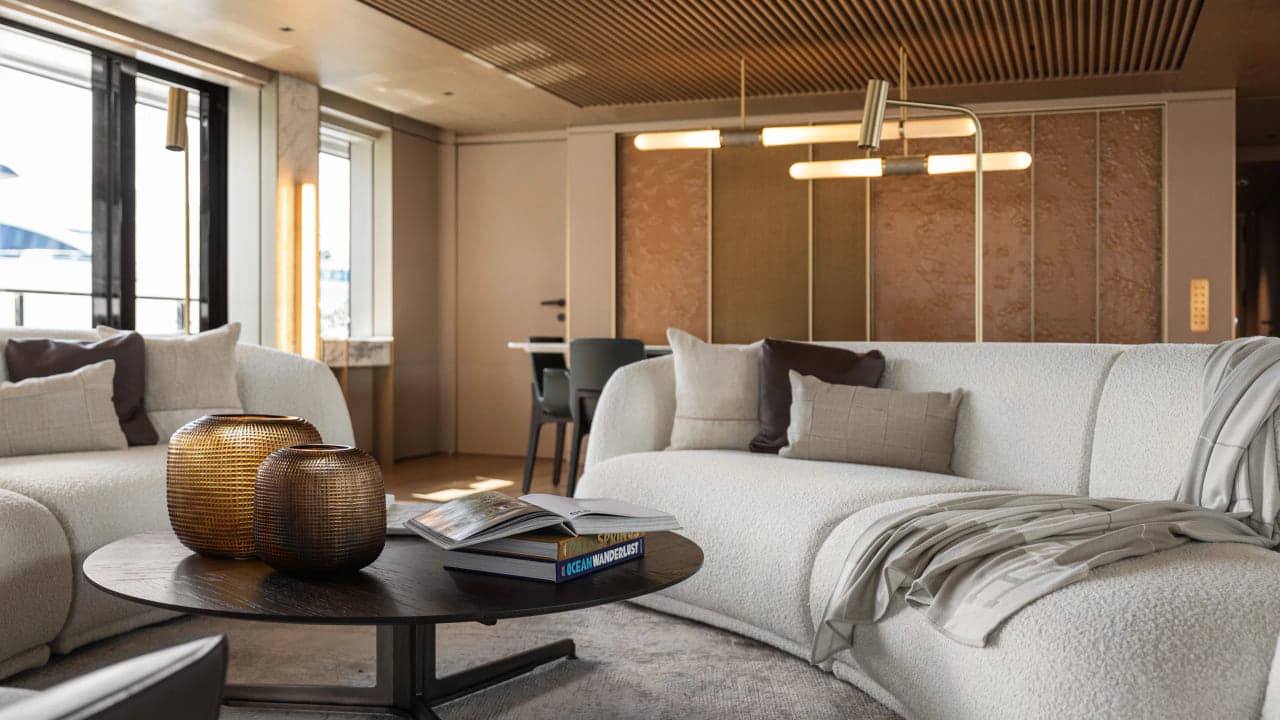 Luxury living room with a bouclé sofa, a round bronze coffee table, brass pendant lighting and warm wood paneling, the kind of material program a navy sofa has to answer to