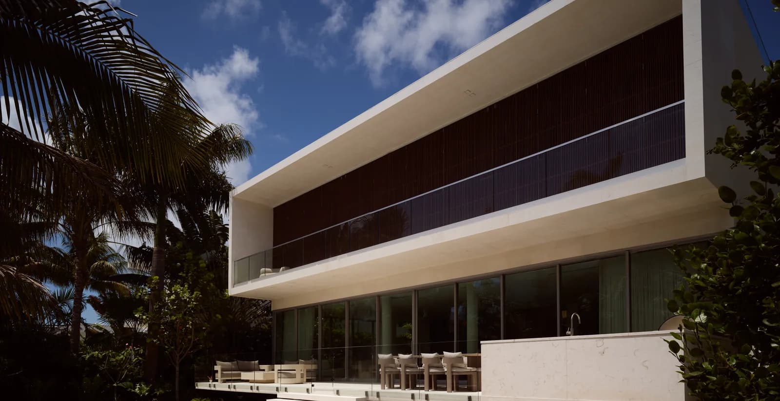 The cantilevered facade and ground floor terrace of the Broadview Residence in Coconut Grove, Miami, where the exterior living space connects the house to the pool and lounge area