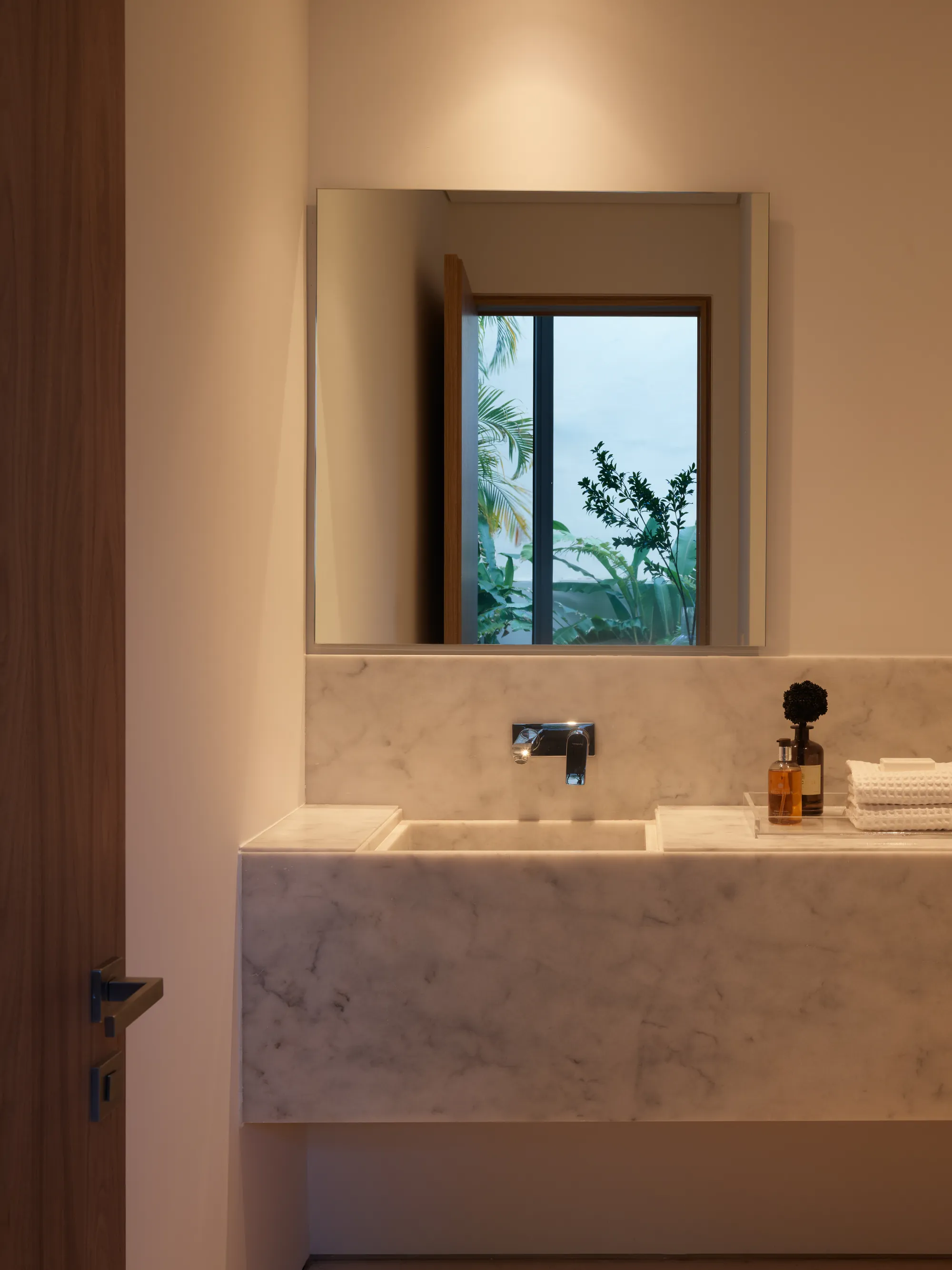 Open walk-in shower with no door in a stone-clad primary bathroom in the Onaway residence by LUXOM, Miami