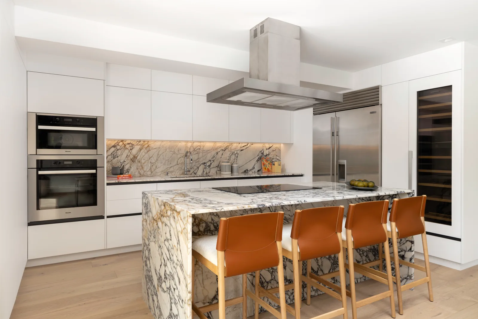 Kitchen with a natural-stone island and integrated hood in the Samana residence by LUXOM